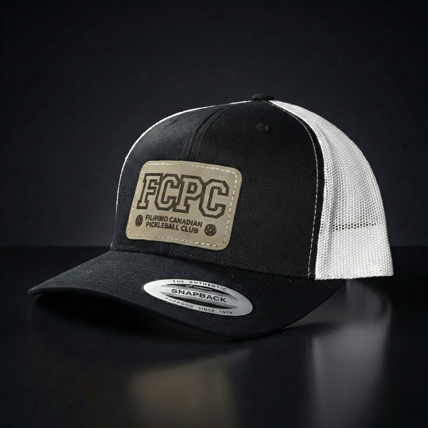 Black and white trucker cap with FCPC logo on a dark background