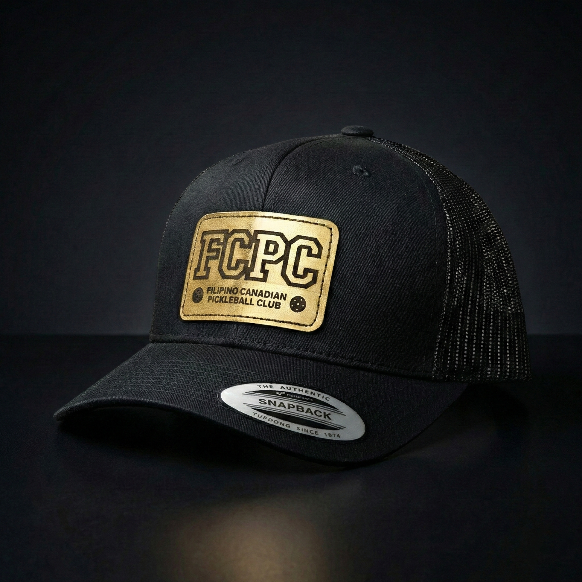 Black cap with gold patch on a dark background